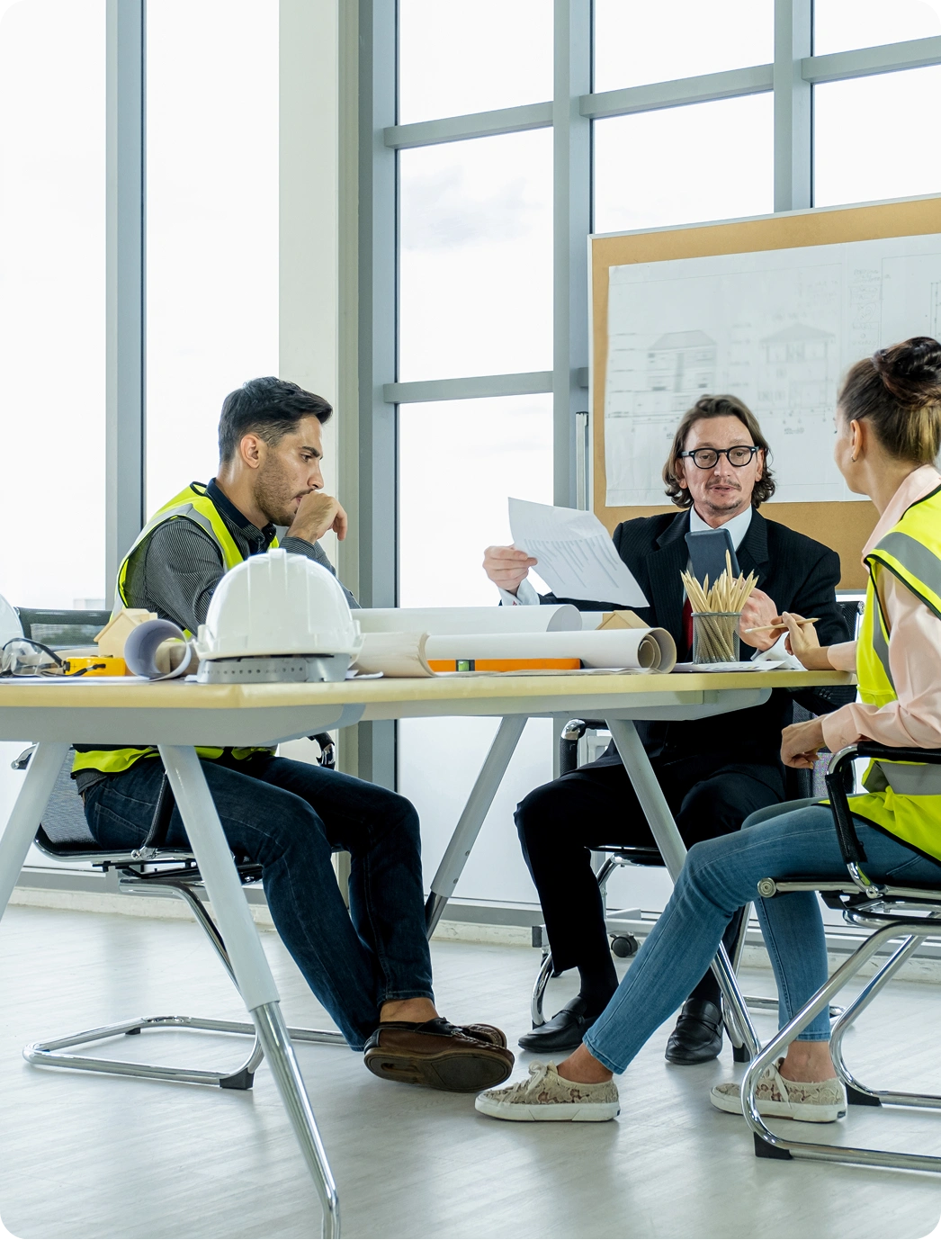 Trzy osoby – dwóch inżynierów w kamizelkach i ekspert bhp przeglądają dokumenty planów – doradztwo bhp